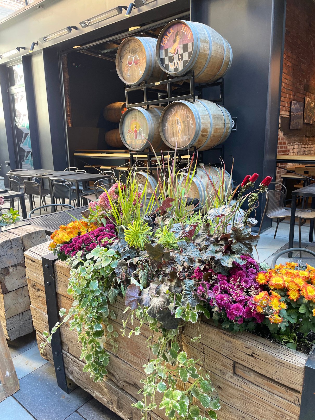 flowers in a wooden planter in front of wine barrels; flowers in downtown Denver; flowers outside a restaurant; plants that attract customers